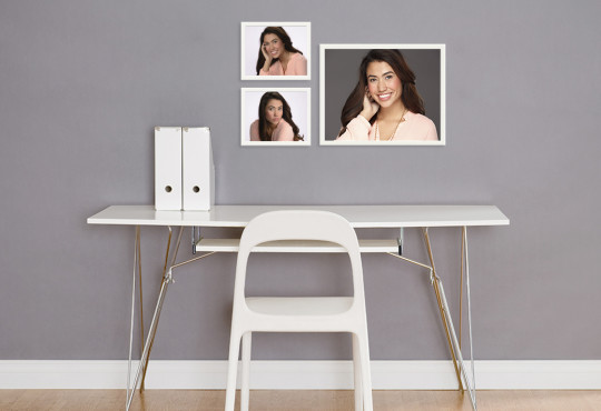 Framed senior portraits of girl hanging on wall in front of white desk