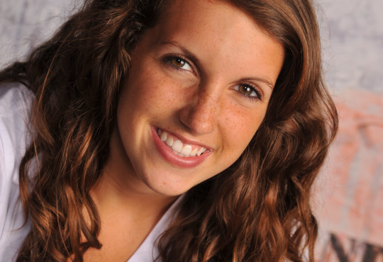 A girl smiling wearing a white shirt