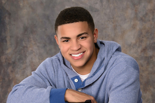 A boy smiling wearing a blue sweatshirt