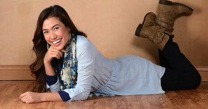 A girl smiling wearing blue dress laying on floor