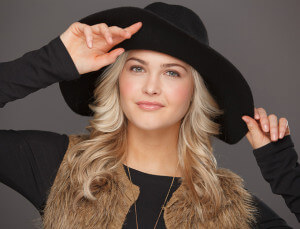 A girl posing in black shirt and black hat