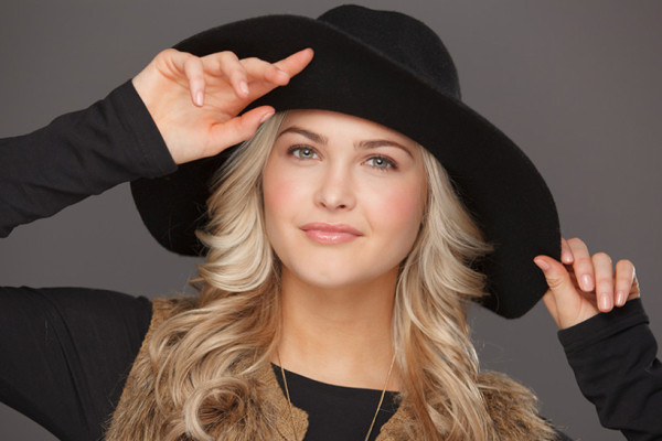 A girl posing in black shirt and black hat